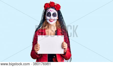 Woman wearing day of the dead costume holding blank empty banner looking positive and happy standing and smiling with a confident smile showing teeth 