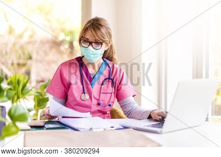 Shot Of Careworn Female Doctor Wearing Face Mask For Prevention While Sitting At Desk And Working On