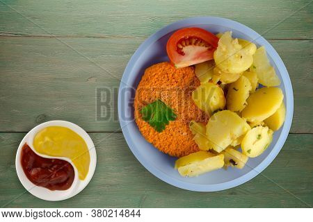 Meatball With Potatoes On Green Wooden Background. Meatball With A Slice Of Tomato On Light Blue Pla