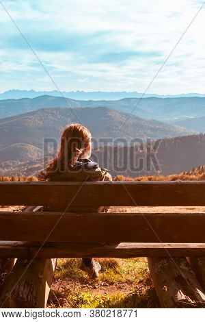 A Lonely Girl Sits On A Bench And Enjoys The Stunning View Of The Autumn Mountains