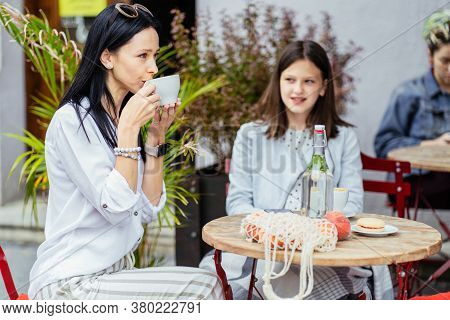 Mom And Her Teenager Grown Up Daughter Drink Coffee, Stiitng At Outdoor Cafe, Trying Socializing. Se