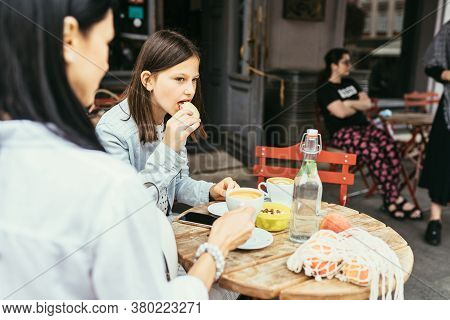 Mom And Her Teenager Grown Up Daughter Drink Coffee, Stiitng At Outdoor Cafe, Trying Socializing. Se