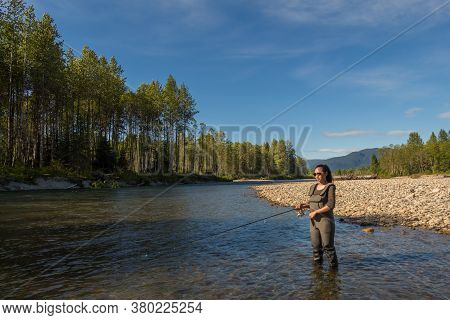 An Asian Women In Waders, Fishing The Kitimat River, Skeena Region, In British Columbia, Canada