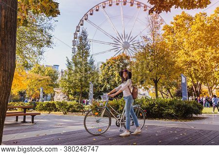 A Happy Young Woman Travel By Bicycle And Stop Near The Budapest Eye Big Ferris Wheel In Budapest
