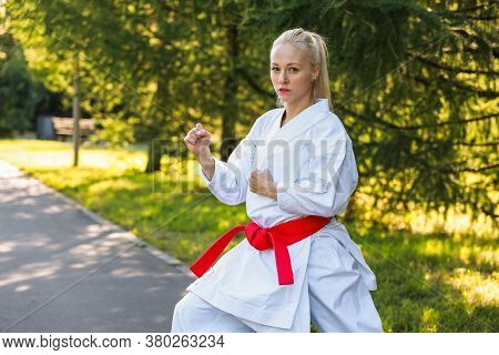 Young Woman Dressed In Kimono Practicing Her Karate Moves In Park - Red Belt