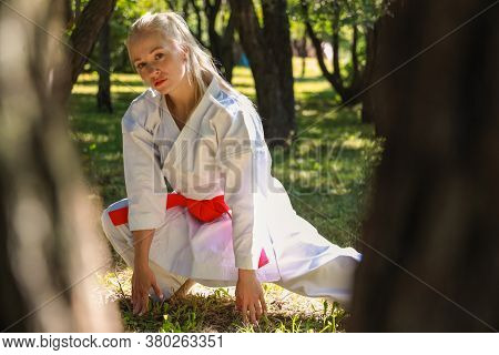 Young Woman Dressed In Kimono Practicing Her Karate Moves In Park - Red Belt