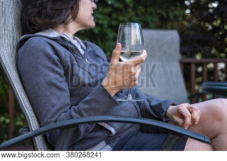 Woman Drinking A Glass Of White Wine On Her Backyard Deck