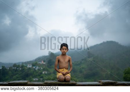 A Young Indian Cute Kid Doing Yoga In The Mountains,wearing A Dhoti
