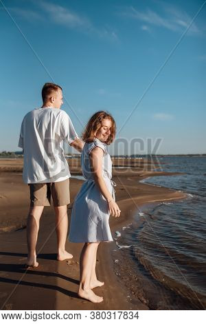 Couple In Love On The Beach.young Man And Woman Walking On Seashore And Laughing.