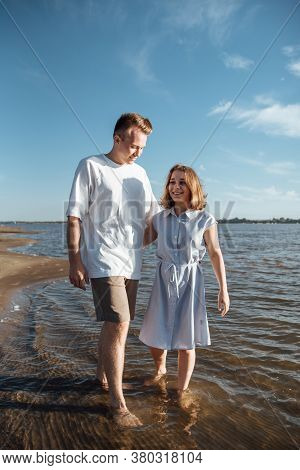 Couple In Love On The Beach.young Man And Woman Walking On Seashore And Laughing.