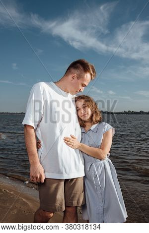 Couple In Love On The Beach.portrait Of A Couple In Love On The Beach. A Young Girl Hugs A Guy.