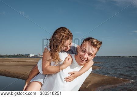Couple In Love On The Beach.portrait Of A Couple In Love On The Beach. A Young Girl Hugs A Guy.