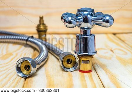 Cruciform Hot And A Cold Water Main Switch Of Spare Parts On Wooden Boards