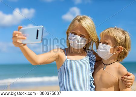 Funny Kids Taking Selfie Photo By Smartphone On Tropical Sea Beach. New Rules To Wear Cloth Face Cov