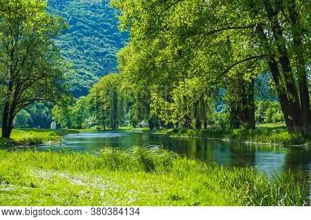 Croatia, Beautiful River Gacka Flowing Between The Green Meadow Fields In Lika Region