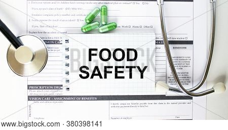 Text Food Safety In A Notebook On Medical Forms With A Phonendoscope And Green Pills