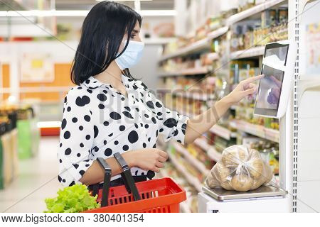 Young Woman In A Disposable Medical Mask Is Shopping At The Supermarket. Weighs Potatoes On A Self-s