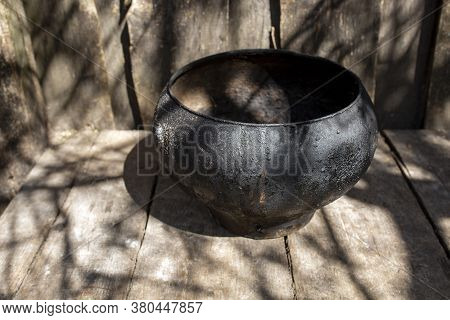 Vintage Cast-iron Pot Of Black Color On Wooden Boards On A Sunny Day Outdoor. Cooking Food.