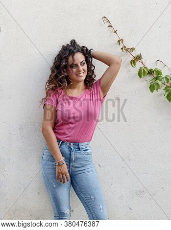 Young Women Wearing T-shirt And Jeans Stays Near A Wall And Smile