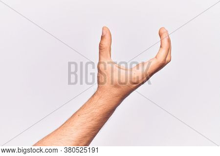 Close up of hand of young caucasian man over isolated background picking and taking invisible thing, holding object with fingers showing space 