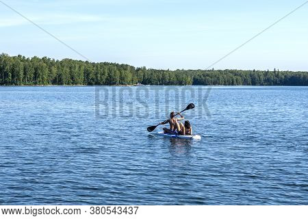 Young Women Swim Together On A Sup Board In The Calm Bay Of The Lake. July 12, 2020 Lake Uvildy, Ura