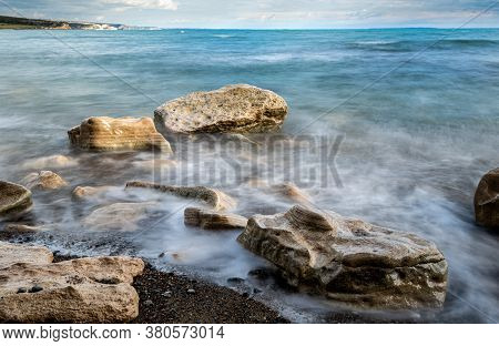 Seawaves Splashing Onto The Sandy Coast With Pebbles And Blue Cloudy Sky. Melanda Coast , Pissouri C
