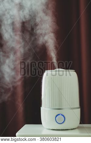 White Ultrasonic Humidifier On The Bedside Table On A Dark Background. Water Vapor.