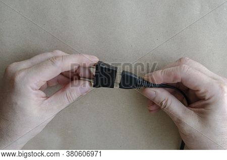 An Adult Caucasian Male Is Holding Power Plug Adapter. Black Ac And Dc Power Adapter. View From Abov