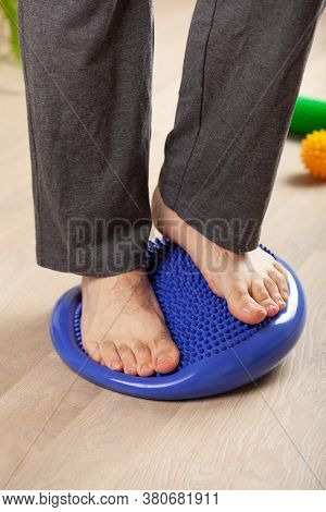 man doing flatfoot correction gymnastic exercise balancing on massage cushion at home
