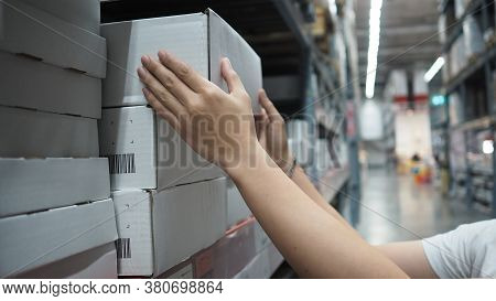 Warehouse Large Storage Or Logistic Or Cargo For Distribution. And Man's Hand Is Picking Up A Box.