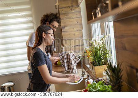 Beautiful Young Couple In Love Doing The Washing Up And Drying Together After Lunch; Couple Washing 