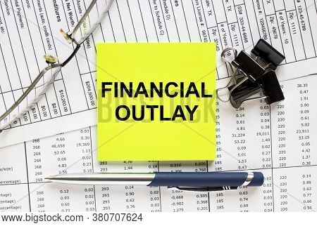 Text Financial Outlay On Financial Tables With Pen, Glasses And Paper Clips