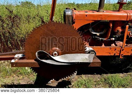 A Huge Rusty Saw Blade Is Mounted On A Tractor With A Leather Belt Too Be Attached To The Belt Pulle