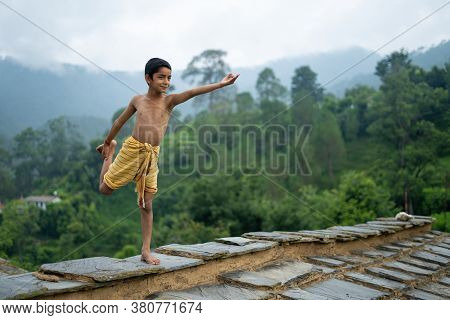 A Young Indian Cute Kid Doing Yoga In The Mountains,wearing A Dhoti