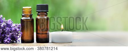 Bottles Of Essential Oil With Lavender Flower And Canddle Arranged On A Wooden Table On Green Backgr