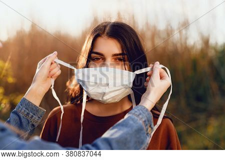 Beautiful Women In A Medical Mask. Close-up Of A Young Woman With A Surgical Mask On Her Face Agains