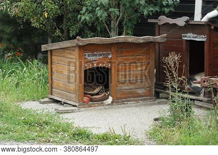 One Large Empty Brown Wooden Doghouse Stands Outside In The Green Grass
