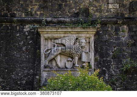 Winged Lion Of Venice On Kotor City Wall, Former Venetian Fortress In Montenegro. Latin Words On The