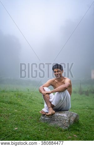 Young Handsome Asian Model Sitting In The Mountains Wearing A Dhoti In The Morning Time.