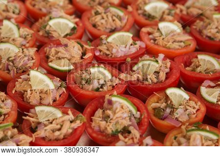 Buffet Appetizer: Tomatoes Stuffed With Canned Tuna And Onions, Garnished With A Slice Of Lemon