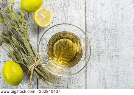 Glass Cup Of Herbal Sage Tea With Dried Sage Leaves And Lemon On White Wooden Rustic Background. Her
