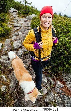 Woman Hiking In Mountains And Walking Akita Dog