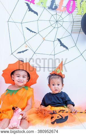 Funny Happy Brethren Baby Girl And Kid Boy In Halloween Costume With Pumpkin Jack With Cobweb On Bac