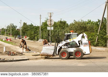 Workers Are Repairing The Road, Changing The Asvalt, Laying Paving Slabs In A Small Town In The Summ