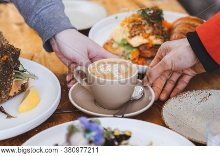 A Cup Of Flatwhite Coffee In Cream Ceramic Cup With Latte Art On Top, Touched By Two Hands, Surround