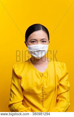 Asian Woman Wearing Protective Face Mask Isolated On Yellow Background.
