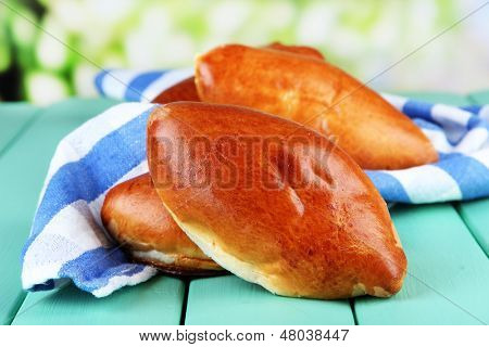 Empanadillas al horno frescos, en mesa de madera, sobre fondo brillante