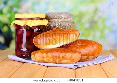 Empanadillas al horno frescos con mermelada de frutas, en la mesa de madera, sobre fondo brillante