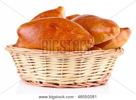 Empanadillas al horno frescos en cesta de mimbre, aislados en blanco