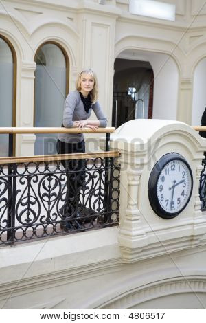 Attraktive Frau Stand am Geländer neben Uhr. Warten